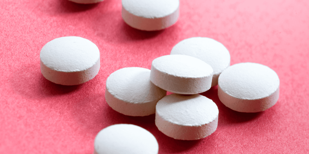 White pills lay on a pink background