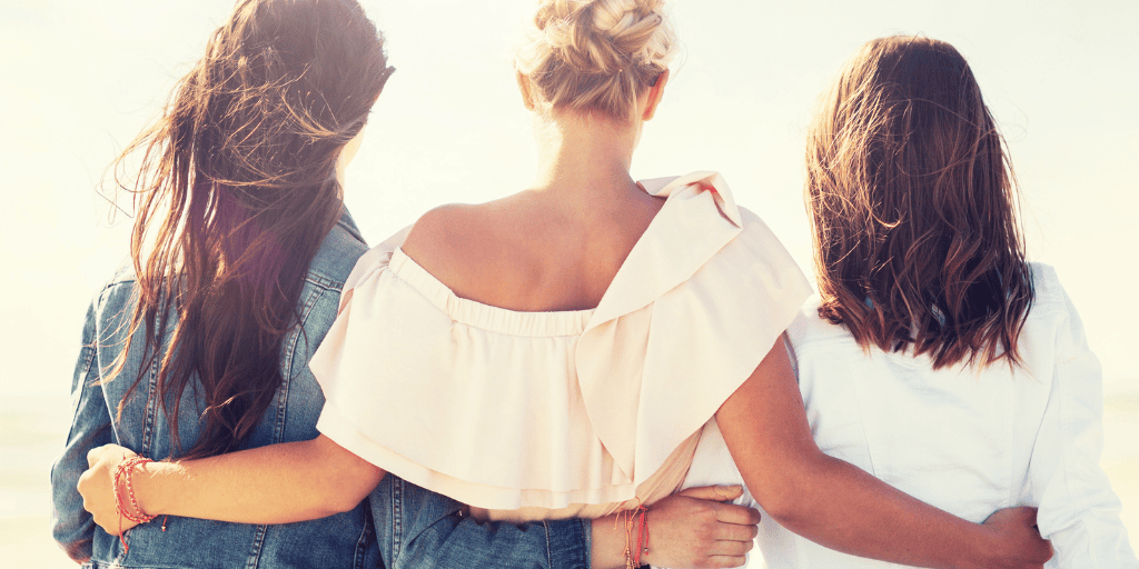 3 women place arms around each other supportively