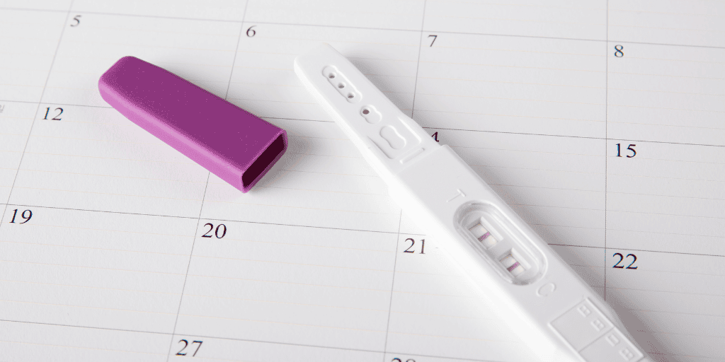 Can I get pregnant during my period? Pregnancy test laying on calendar 