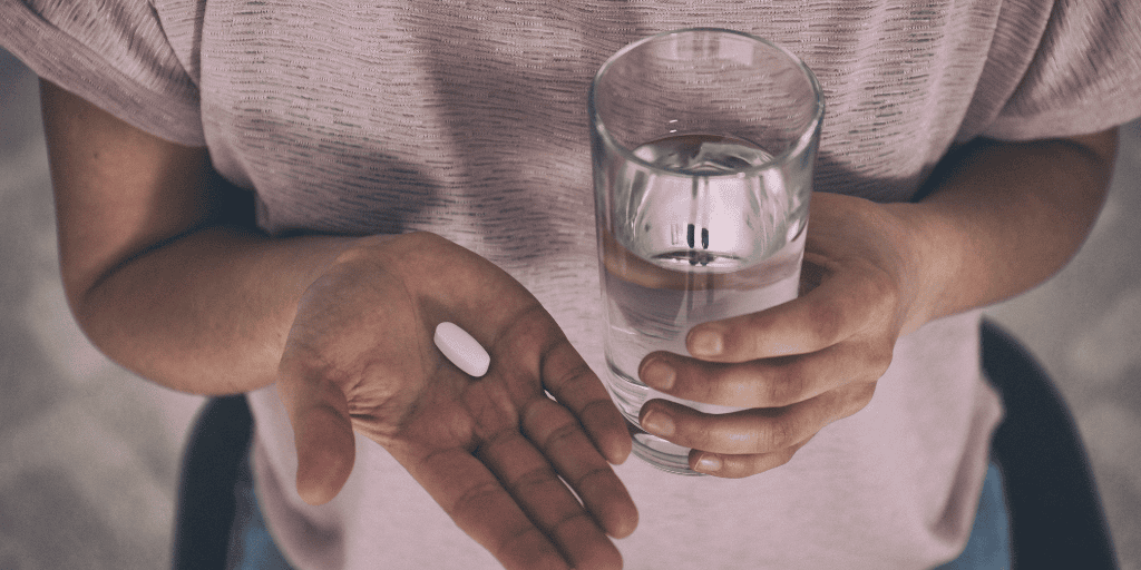 woman holding the abortion pill and a glass of water